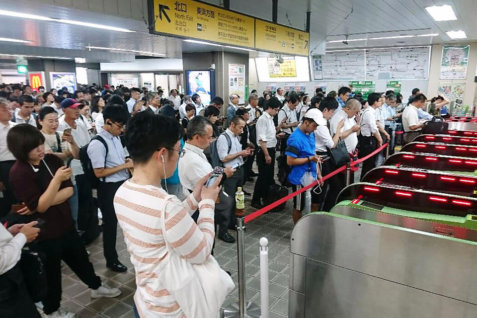 People wait for train operation to resume as it was suspended typhoon in Urayasu, east of Tokyo, Monday, Sept. 9, 2019.. (Kyodo News via AP)