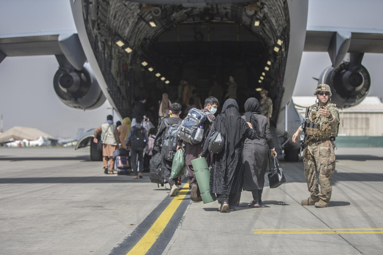 In this image provided by the U.S. Marine Corps, families begin to board a U.S. Air Force Boeing C-17 Globemaster III during an evacuation at Hamid Karzai International Airport in Kabul, Afghanistan, Monday, Aug. 23, 2021. (Sgt. Samuel Ruiz/U.S. Marine Corps via AP)
