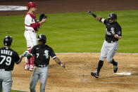 Chicago White Sox's Adam Eaton, right, scores after hitting a two-run home run as shortstop Tim Anderson, second from right, is congratulated by Jose Abreu, left, and Los Angeles Angels catcher Max Stassi watches during the fifth inning of an Opening Day baseball game Thursday, April 1, 2021, in Anaheim, Calif. (AP Photo/Mark J. Terrill)