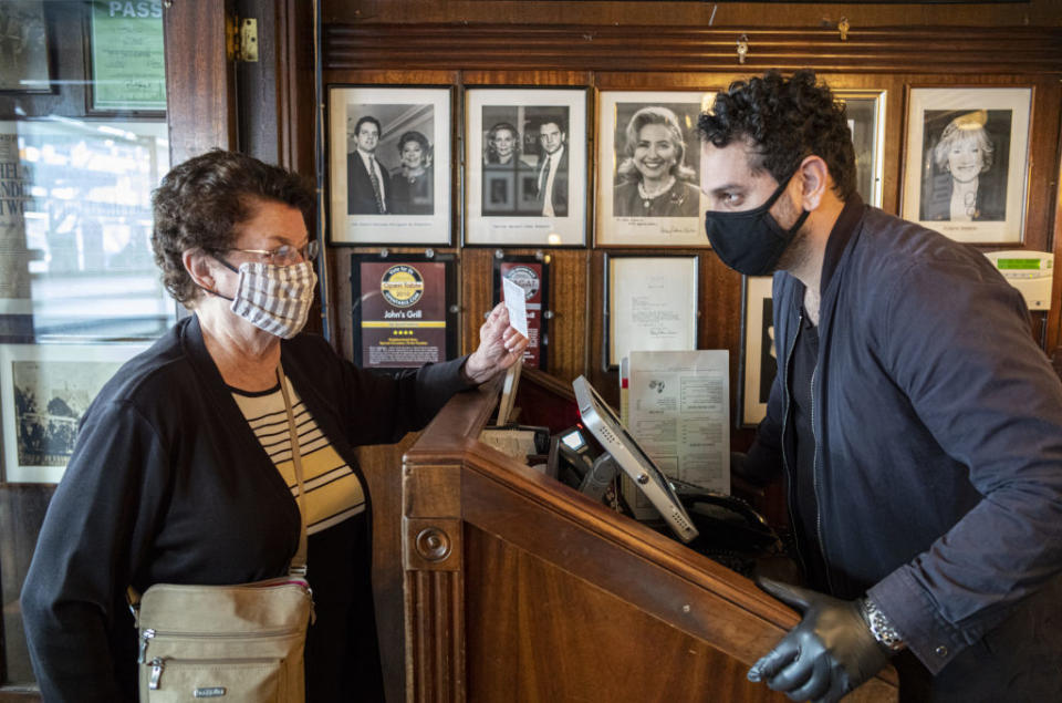 A customer shows a proof of vaccination card to a worker at Johns Grill restaurant vaccination requirements are in effect in San Francisco, California, US.