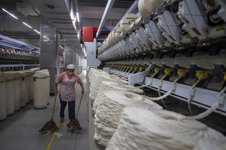 A worker sweeps loose cotton near a production line at the Wenzhou Tiancheng Textile Company, one of China's largest cotton recycling plants in Wenzhou in eastern China's Zhejiang province on March 20, 2024. (AP Photo/Ng Han Guan)