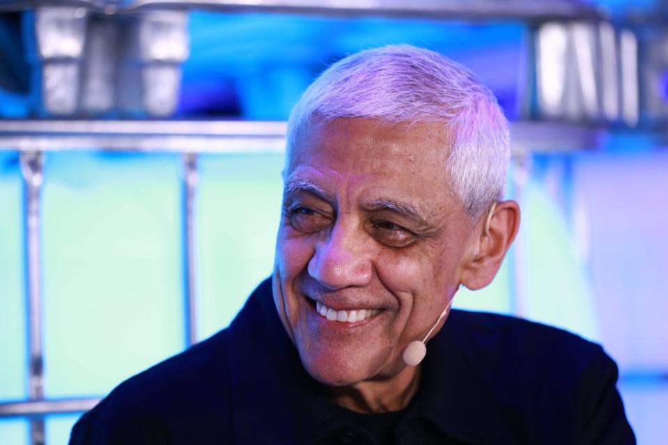 Vinod Khosla, Founder, Khosla Ventures, smiles at an event. He is wearing a mic and dark suit.