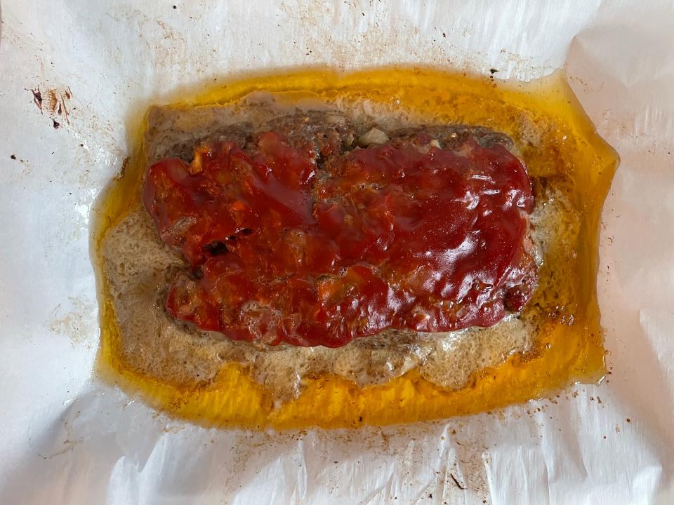 Meat loaf in a pan surrounded by grease.