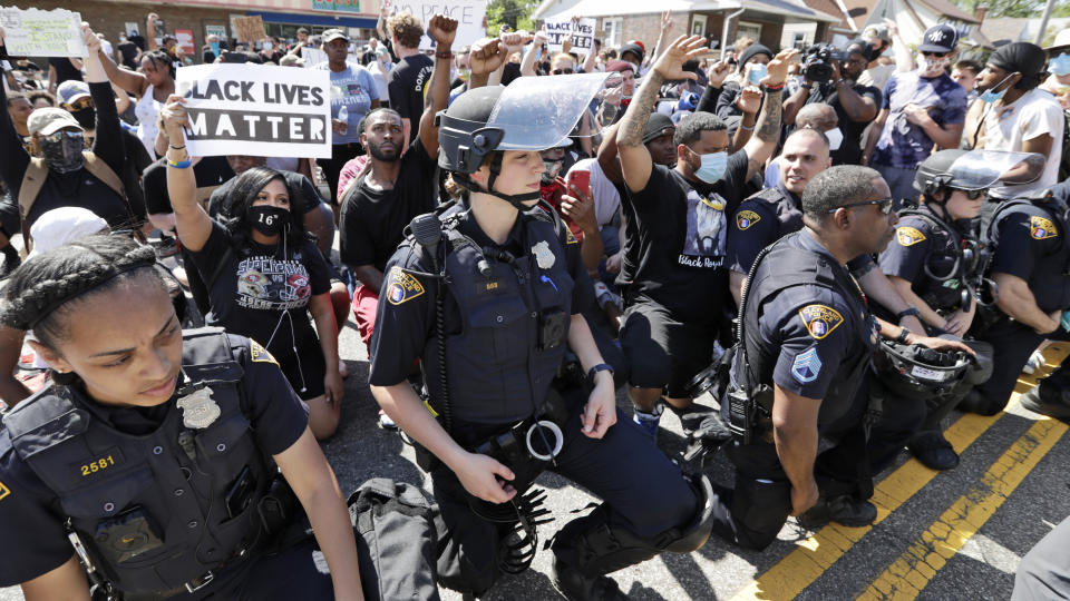 FILE - In this June 2, 2020, file photo, Cleveland police officers and protesters take a knee together during a rally for black lives, in Cleveland. George Floyd, a black man, died after being restrained by Minneapolis police officers on May 25 and his death sparked protests. Black officers find themselves torn between two worlds when it comes to the protests against police brutality happening around the U.S. (AP Photo/Tony Dejak)