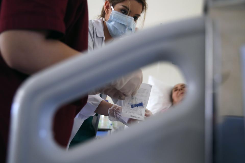 In this photo taken on Wednesday, May 6, 2020, medical student Eleni Fyta takes blood test from a patient at the Pathological Clinic of Sotiria Hospital in Athens. Greece's main hospital for the treatment of COVID-19 is also the focus of a hands-on training program for dozens of medical students who volunteered to relieve hard-pressed doctors from their simpler duties while gaining a close peek at the front lines of a struggle unmatched in modern medical history. (AP Photo/Thanassis Stavrakis)