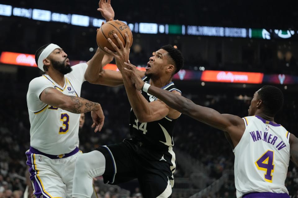 during Milwaukee Bucks' Giannis Antetokounmpo is fouled driving between Los Angeles Lakers' Anthony Davis and Lonnie Walker IV the first half of an NBA basketball game Friday, Dec. 2, 2022, in Milwaukee. (AP Photo/Morry Gash)