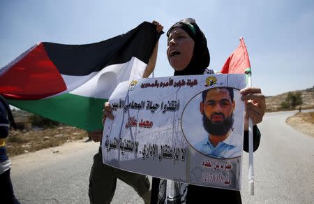 A Palestinian woman holds a picture depicting Palestinian detainee Mohammed Allan during a protest in solidarity with Allan, in the West Bank village of Nabi Saleh, near Ramallah August 14, 2015. REUTERS/Mohamad Torokman