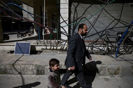 Residents walk past water pipes in the rebel-held Douma neighbourhood of Damascus, Syria March 7, 2016. REUTERS/Bassam Khabieh