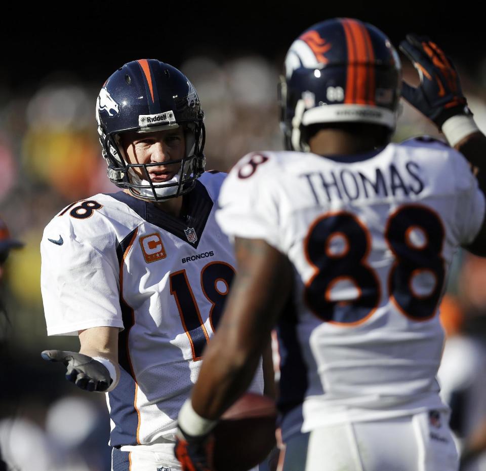 Denver Broncos quarterback Peyton Manning (18) celebrates with wide receiver Demaryius Thomas (88) after they connected for a 5-yard touchdown against the Oakland Raiders during the second quarter of an NFL football game, Sunday, Dec. 29, 2013, in Oakland, Calif. With that completion, Manning set the all-time single season passing yardage record. (AP Photo/Marcio Jose Sanchez)