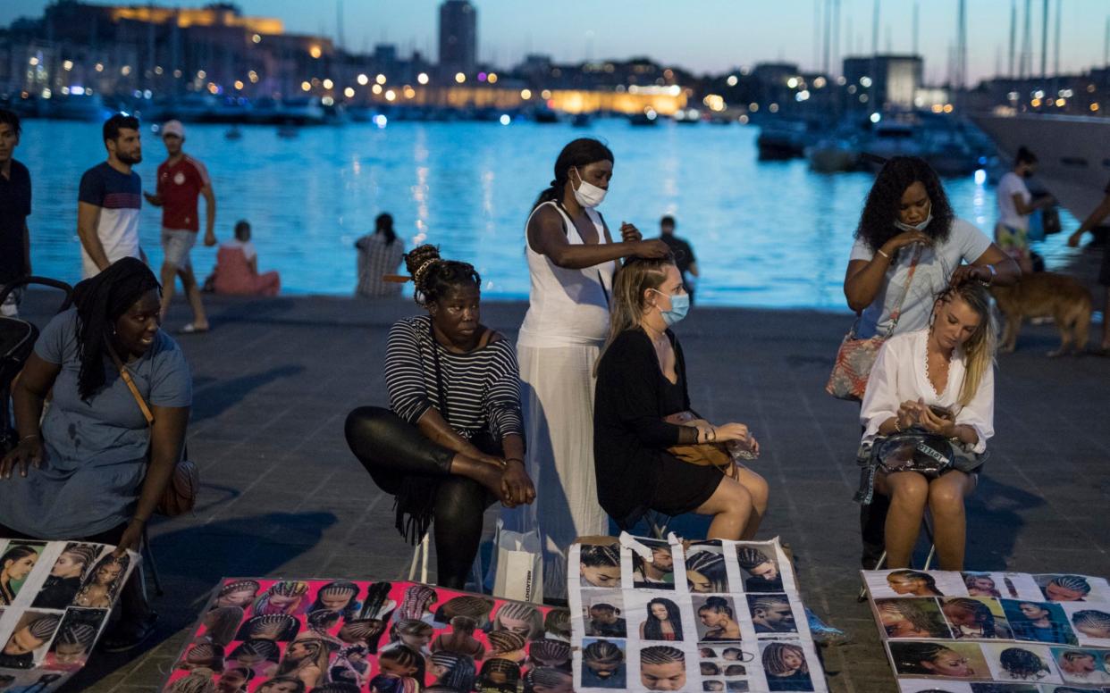 Tourists get their hair braided in Marseille's Old Port as France reported more than 1,000 new infections on Thursday - Daniel Cole/AP