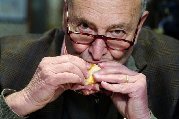 Sen. Chuck Schumer says New Yorkers want life to return to normal. Indoor dining is expanding closer to full capacity this week, and here Schumer takes a bite of a sandwich at Junior's restaurant in Times Square in New York City on Thursday. 