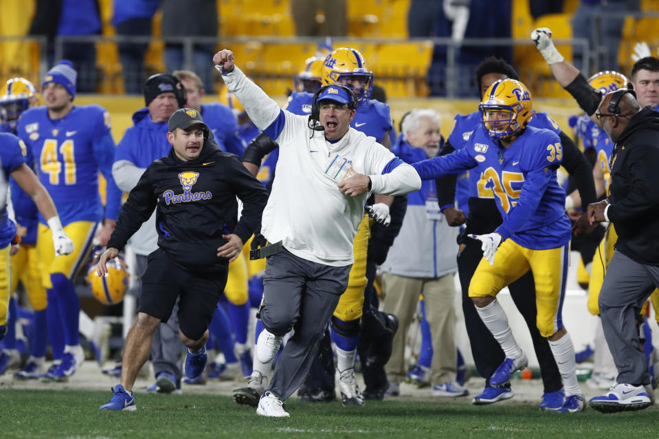 Pittsburgh coach Pat Narduzzi, center, celebrates with his team as they run onto the field after a fourth-down pass by North Carolina quarterback Sam Howell fell incomplete in the end zone during overtime of an NCAA football game Thursday, Nov. 14, 2019, in Pittsburgh. Pittsburgh won 34-27. (AP Photo/Keith Srakocic)