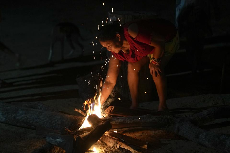 Borea Juma lights firewood to grill fish in the Juma Indigenous community near Canutama, Amazonas state, Brazil, Saturday, July 8, 2023. Along with two sisters, Borea leads and manages the Indigenous territory after the death of their father in 2021. (AP Photo/Andre Penner)