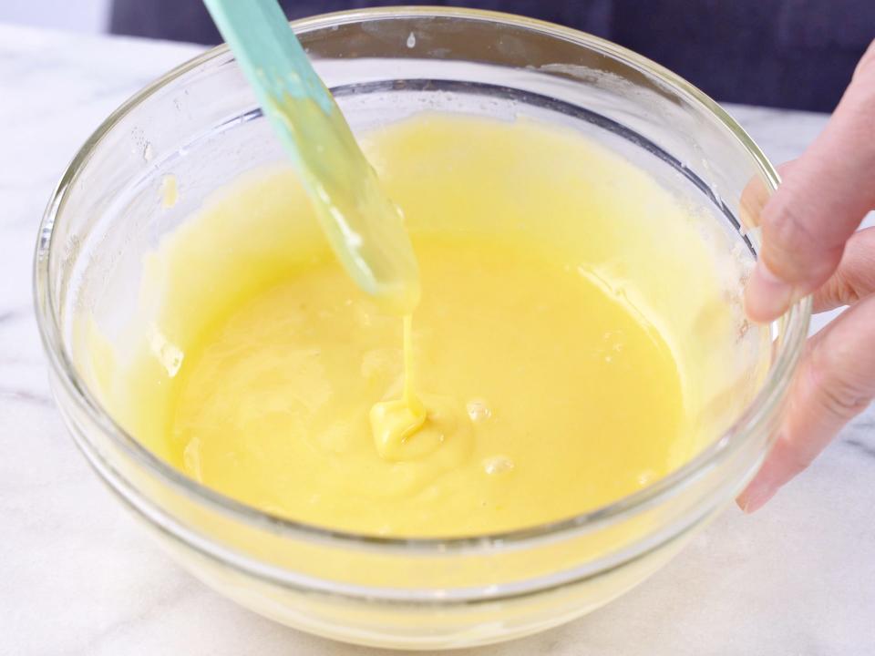 a person mixing Lemon Curd in clear bowl with baking spatula