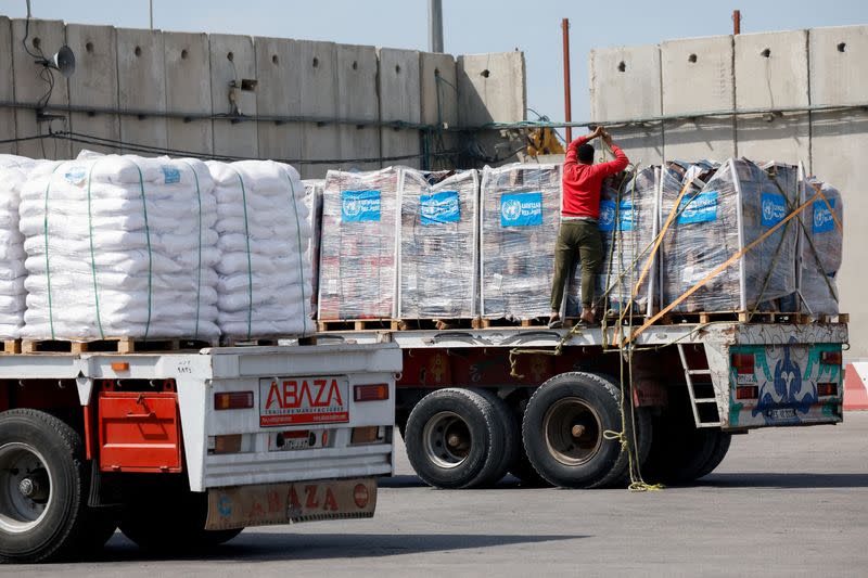 FILE PHOTO: A driver adjusts a rope as he stands on a truck carrying humanitarian aid bound for the Gaza Strip at the Kerem Shalom crossing
