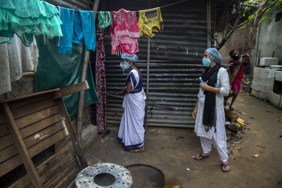 Heath workers call a woman, unseen, who does not agree to give swab sample to test for COVID-19 in a slum in Gauhati, Assam, India, Monday, May 17, 2021. (AP Photo/Anupam Nath)