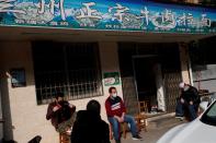 Staff sit in front of a closed restaurant after eateries were closed citywide because of the coronavirus outbreak in Jiujiang