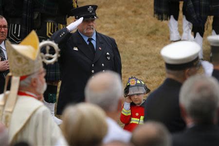 Robert (R), nephew of Boston Fire Department Lieutenant Edward Walsh, salutes as his uncle's casket is carried out of Saint Patrick's church following his funeral in Watertown, Massachusetts April 2, 2014. REUTERS/Brian Snyder