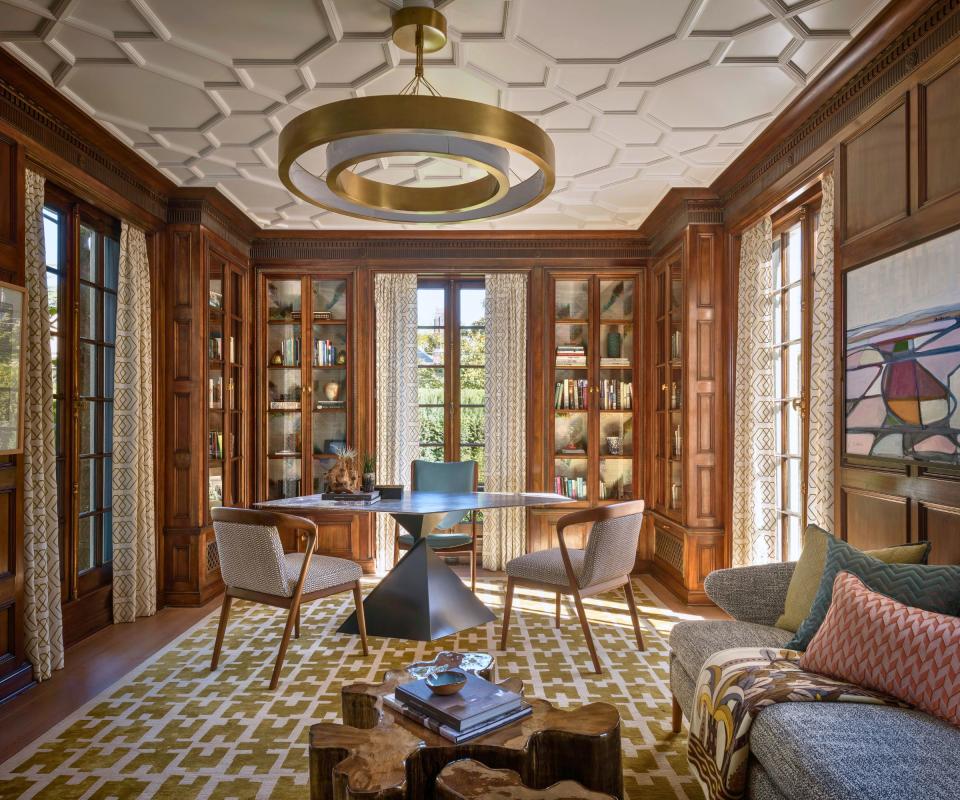 study with decorative ceiling and dark wood paneling and round table