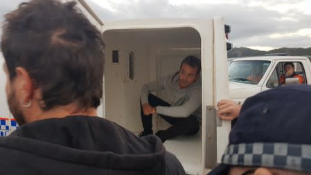 French TV reporter Hugo Clement is seen in a police van after he was arrested while filming protesters blockading the Abbot Point coal port near Bowen