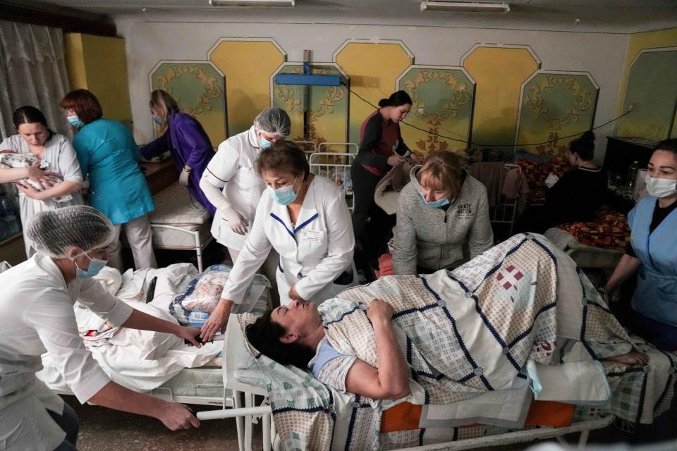 Medical workers move a patient in a basement of a maternity hospital converted into a medical ward and used as a bomb shelter in Mariupol, Ukraine, Tuesday, March 1, 2022.