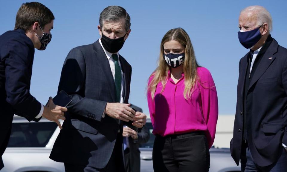 An aide asks Governor Roy Cooper to step back as he greets Joe Biden and his granddaughter Finnegan Biden in Morrisville, North Carolina on Sunday.