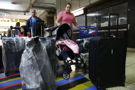 Natalie Pereira (C) queues to go through migration before her move to the U.S. with her family, after winning the Green Card lottery, at the Maiquetia airport in Caracas April 8, 2014. REUTERS/Jorge Silva