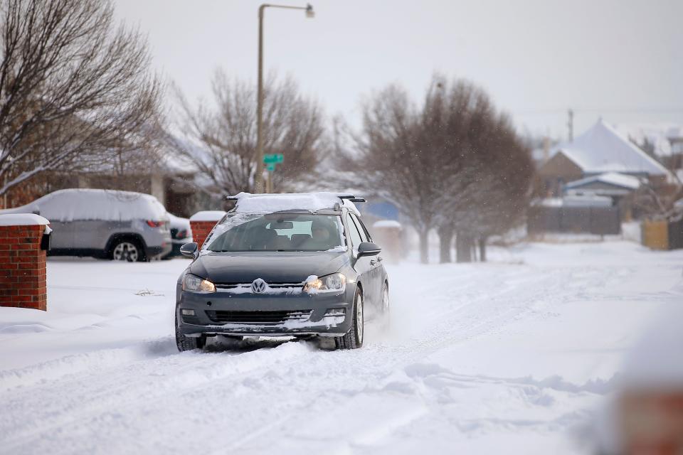 A car drives along a neighborhood street in northwest Oklahoma City after a 2021 winter storm dropped another layer of snow in Oklahoma City.