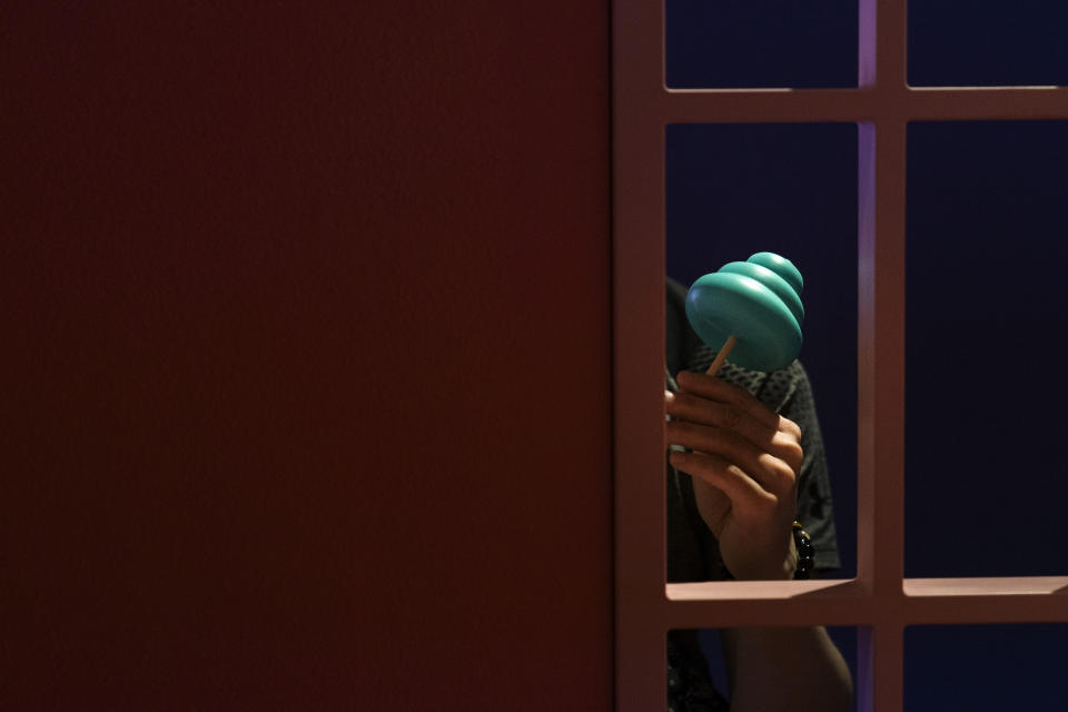 In this Tuesday, June 18, 2019, photo, a man with a poop-shaped figurine on a stick is seen through a window frame at the Unko Museum in Yokohama, south of Tokyo. In a country known for its cult of cute, even poop is not an exception. A pop-up exhibition at the Unko Museum in the port city of Yokohama is all about unko, a Japanese word for poop. The poop installations there get their cutest makeovers. They come in the shape of soft cream, or cupcake toppings. (AP Photo/Jae C. Hong)