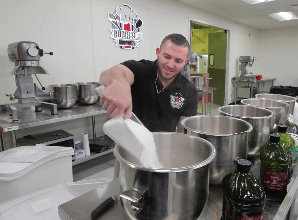 Buckeye Brownies owner Zack Buckeye adds sugar to mixing bowls Tuesday at the company in Akron.