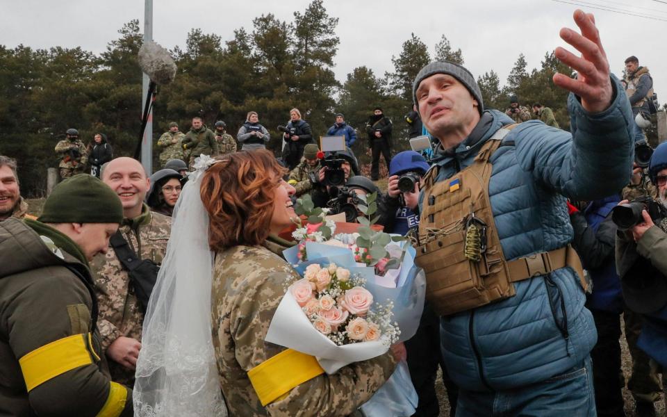 Kyiv's mayor Vitaly Klitschko (R) greets Ukrainian territorial defence fighter Lesya following her wedding with Valeriy (L) - SERGEY DOLZHENKO