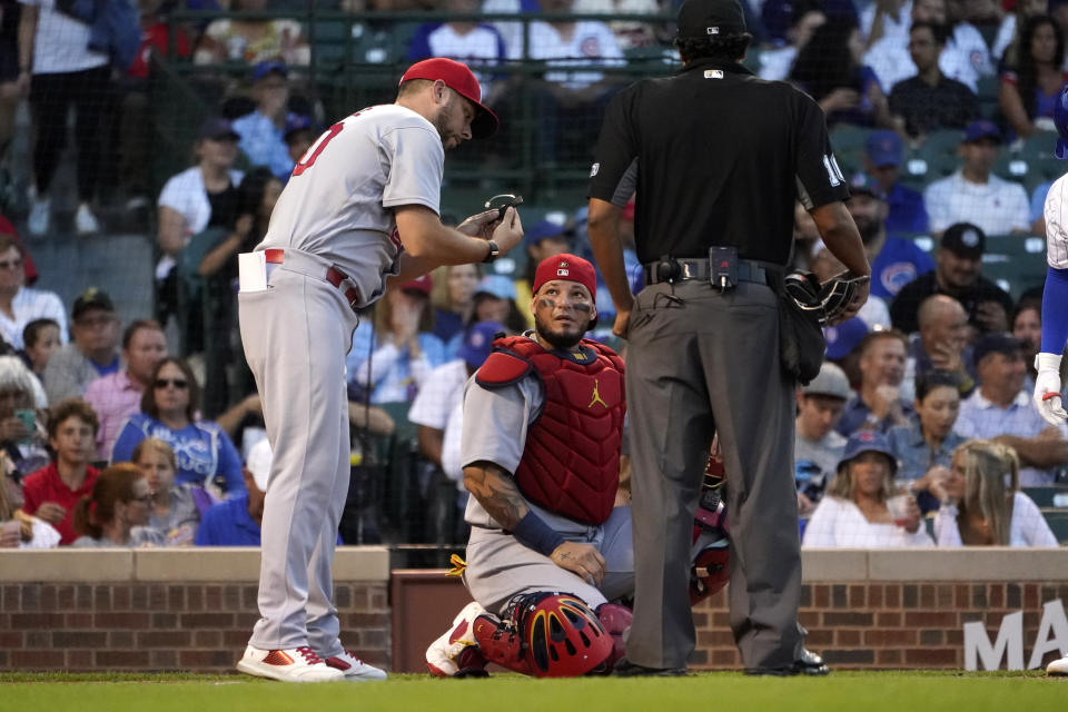 St. Louis Cardinals pitching strategist Dusty Blake, left, checks catcher Yadier Molina's PitchCom during the first inning of a baseball game against the Chicago Cubs, Monday, Aug. 22, 2022, in Chicago. (AP Photo/Charles Rex Arbogast)