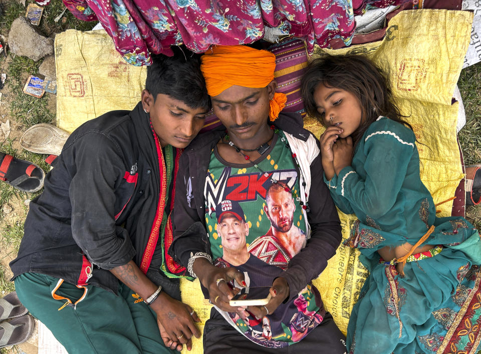 A nomadic family rests in shade outside their tent on a hot summer afternoon in Lalitpur district in northern Uttar Pradesh state, India, Sunday, June 18, 2023. Swaths of two of India's most populous states are under a grip of sever heat leaving dozens of people dead in several days as authorities issue a warning to residents over 60 and others with ailments to stay indoors during the daytime. (AP Photo/Rajesh Kumar Singh)