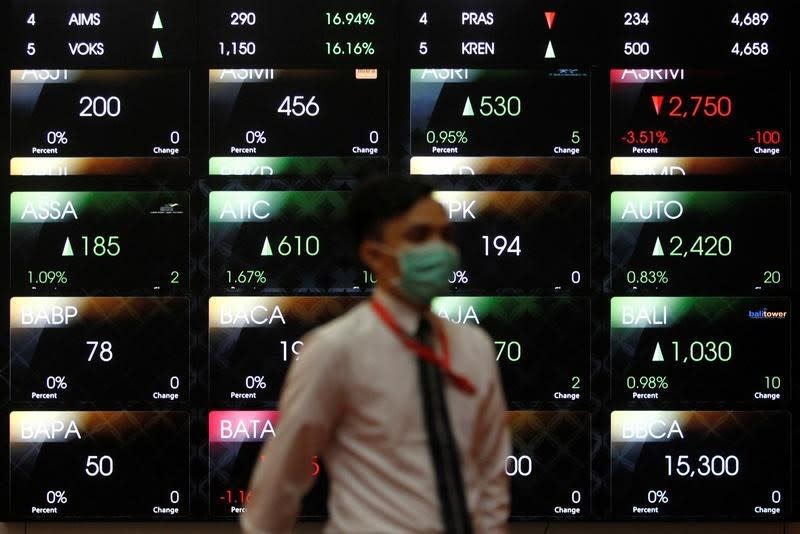 An employee walks in front of an electronic board at the Indonesia Stock Exchange (IDX) in Jakarta, Indonesia August 22, 2016. Picture taken August 22, 2016. REUTERS/Iqro Rinaldi