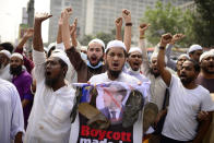 Supporters of Islami Andolan Bangladesh, an Islamist political party, carry a poster of French President Emmanuel Macron with a garland of footwear around it as they protest against the publishing of caricatures of the Prophet Muhammad they deem blasphemous, in Dhaka, Bangladesh, Tuesday, Oct. 27, 2020. Muslims in the Middle East and beyond on Monday called for boycotts of French products and for protests over the caricatures, but Macron has vowed his country will not back down from its secular ideals and defense of free speech. (AP Photo/Mahmud Hossain Opu)