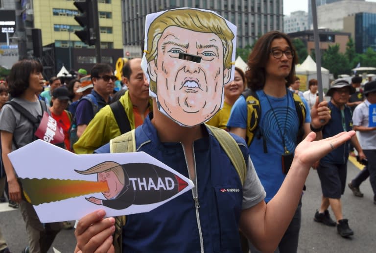 A South Korean protestor wearing a mask of US President Donald Trump marches toward the US embassy during a rally against the deployment of the US Terminal High Altitude Area Defense (THAAD) system