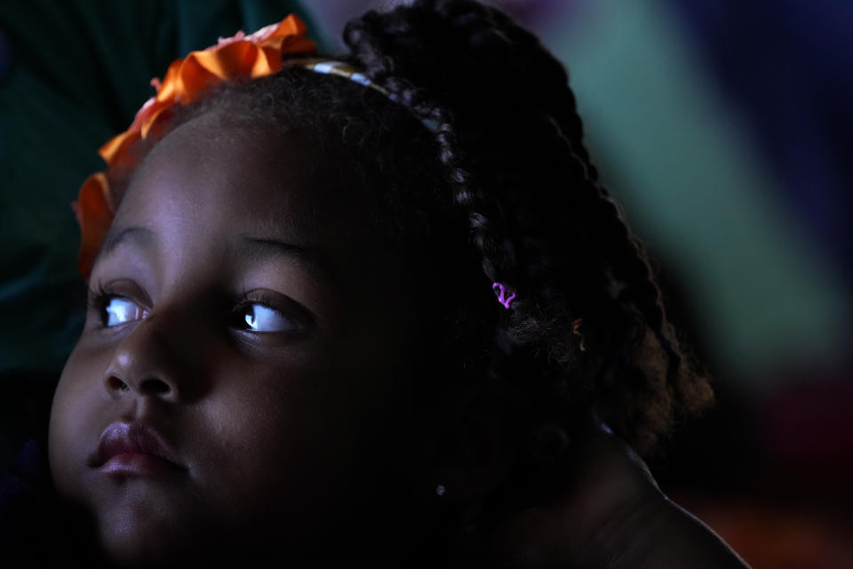 A girl looks on during her baptism in the chapel of the Kalunga quilombo, during the culmination of the week-long pilgrimage and celebration for the patron saint "Nossa Senhora da Abadia" or Our Lady of Abadia, in the rural area of Cavalcante in Goias state, Brazil, Monday, Aug. 15, 2022. Devotees, who are the descendants of runaway slaves, celebrate Our Lady of Abadia at this time of the year with weddings, baptisms and by crowning distinguished community members, as they maintain cultural practices originating from Africa that mix with Catholic traditions. (AP Photo/Eraldo Peres)