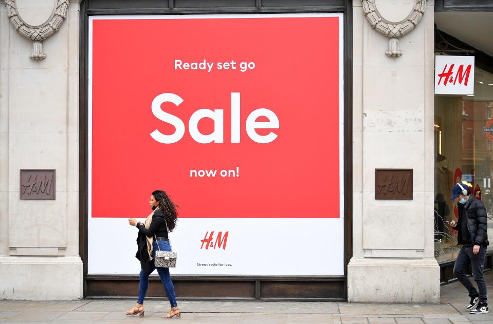 Pedestrians wearing face coverings due to Covid-19, walk past a 'Sale' sign in the window of a closed H&M clothes store on a quiet Oxford Street in central London on March 24, 2021. - Britain's annual inflation rate unexpectedly fell in February as coronavirus curbs sparked heavy discounting for clothing and footwear, official data showed Wednesday, soothing market concerns over inflationary pressures. (Photo by JUSTIN TALLIS / AFP) (Photo by JUSTIN TALLIS/AFP via Getty Images)