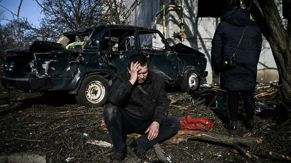 A man sits outside his destroyed building after bombings on the eastern Ukraine town of Chuguiv on February 24, 2022