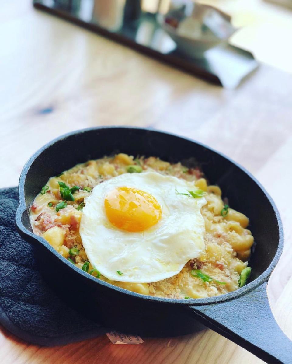 Yolk's Breakfast Mac & Cheese features cheesy mac and cheese mixed with bacon and ham, topped with a panko parmesan crust and a sunny side up egg.