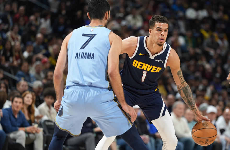 Denver Nuggets forward Michael Porter Jr., right, looks to pass the ball as Memphis Grizzlies forward Santi Aldama defends in the first half of an NBA basketball game, Monday, March 25, 2024, in Denver. (AP Photo/David Zalubowski)