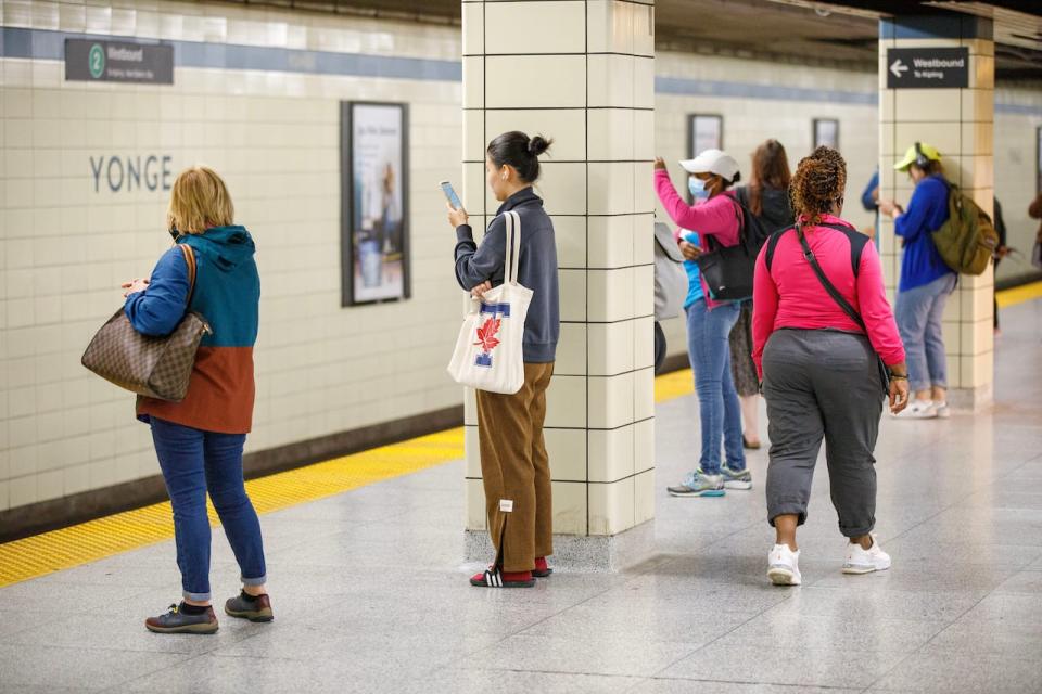 Commuters are photographed on their phones at Yonge Station in Toronto on Aug. 23, 2023.