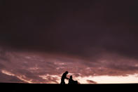 A man pushes a woman in a wheelchair as they stroll along the seawall against the sunset sky while wearing face masks to protect against the coronavirus Sunday, Nov. 22, 2020, in Shizuoka, southwest of Tokyo, Japan. (AP Photo/Kiichiro Sato)