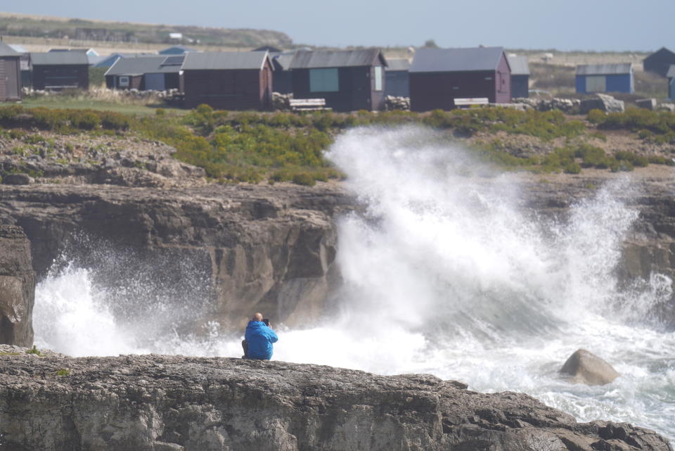 A man photographs waves crashing against the shore in Portland, Dorset, as Storm Antoni is set to bring 