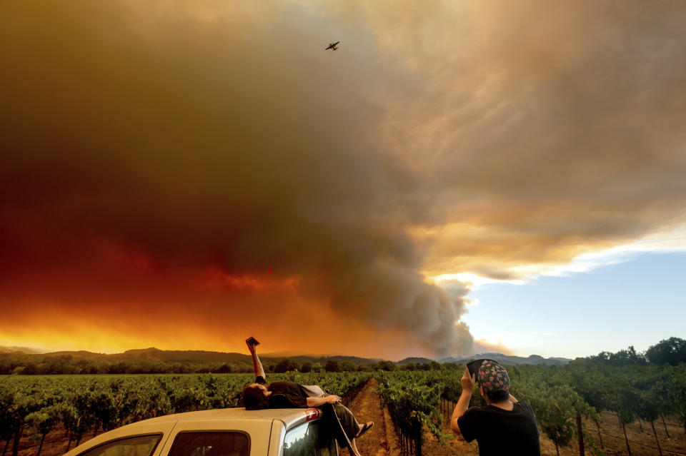 FILE - In this Aug. 20, 2020, file photo, Thomas Henney, left, and Charles Chavira watch a plume spread over Healdsburg, Calif., as the LNU Lightning Complex fires burn. Two unusual weather phenomena combined to create some of the most destructive wildfires the West Coast states have seen in modern times. (AP Photo/Noah Berger, File)