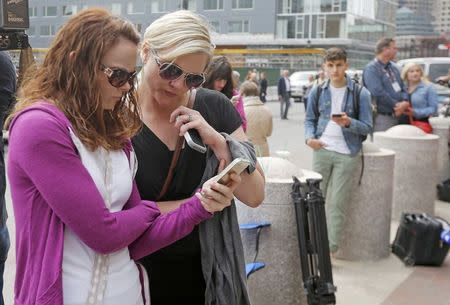 Onlookers check their phones for news on the announcement of the sentencing verdict in the trial of Boston Marathon bomber Dzhokhar Tsarnaev outside the federal courthouse in Boston, Massachusetts May 15, 2015. REUTERS/Brian Snyder