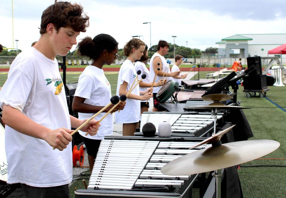 Jupiter High School marching band members Connor Murphy (left), Camille Lyn and Kat Jones play their xylophones during practice on Monday, the day the band received a $15,000 grant from the nonprofit Save Our Musicians.