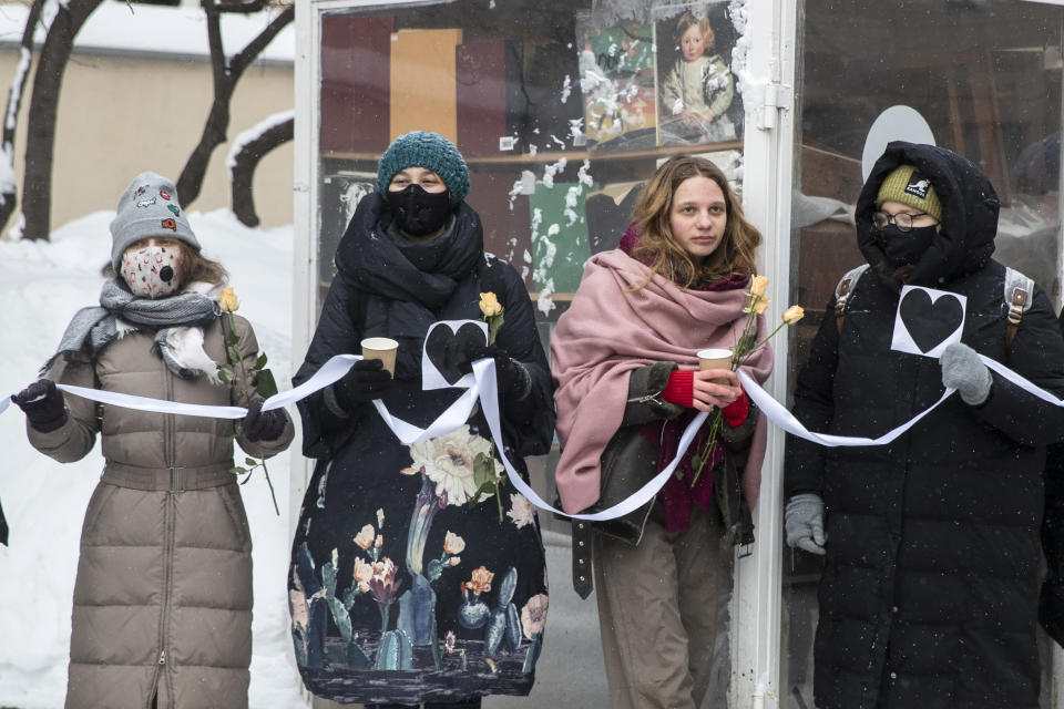 Women hold flowers and a white ribbon as they stand in a line during a rally in support of jailed opposition leader Alexei Navalny and his wife Yulia Navalnaya at Arbat street in Moscow, Russia, Sunday, Feb. 14, 2021. (AP Photo/Pavel Golovkin)