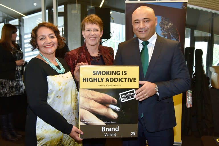 New Zealand Associate Health Minister Sam Lotu-Iiga (R), Wellington mayor Celia Wade-Brown (C) and Maori Party co-leader Marama Fox hold a mock-up of the new plain cigarette packaging in Wellington