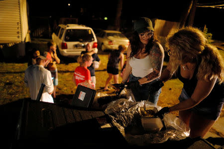 Kate Bailey (L) and Barbara Huang, with 50 Star Search and Rescue, distribute hot food prepared by Operation BBQ Relief to residents following Hurricane Michael in Panama City Beach, Florida, U.S., October 15, 2018. REUTERS/Brian Snyder